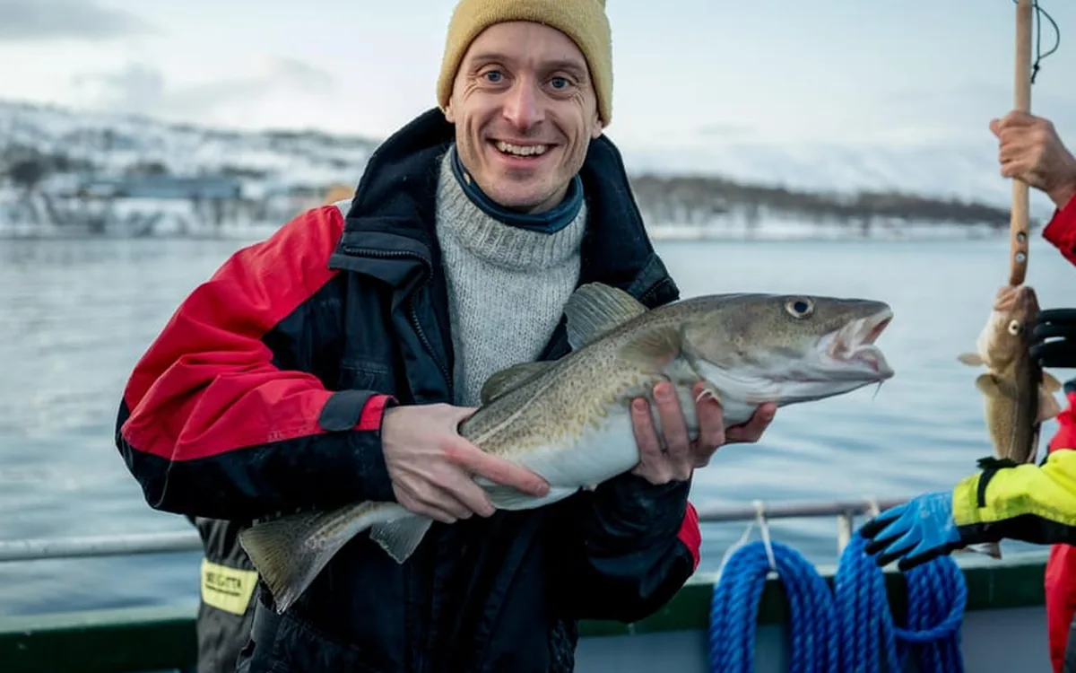 An angler holding a cod caught from the boat