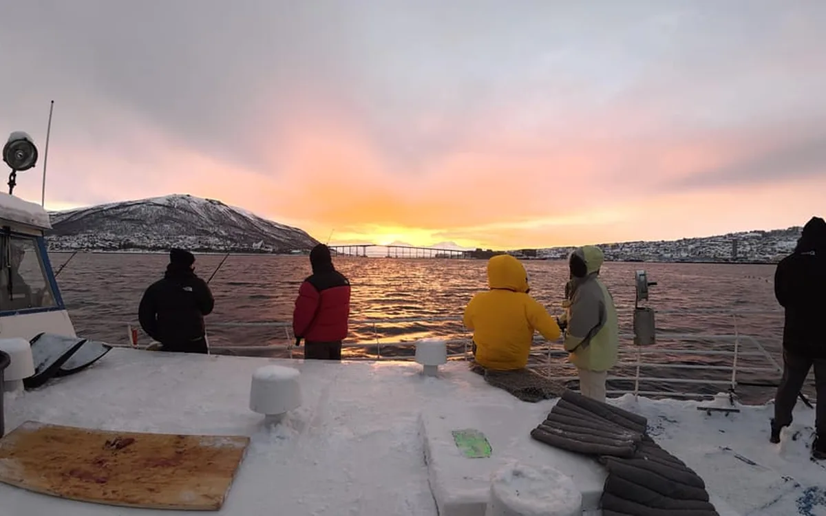 Guests on deck as the sun goes down over the fjord