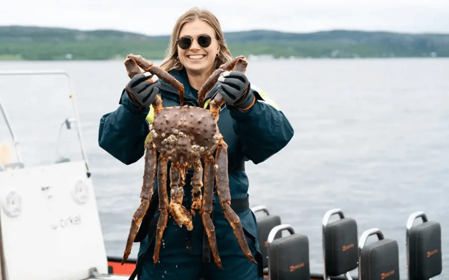 A guest holding a king crab aboard a RIB in summer