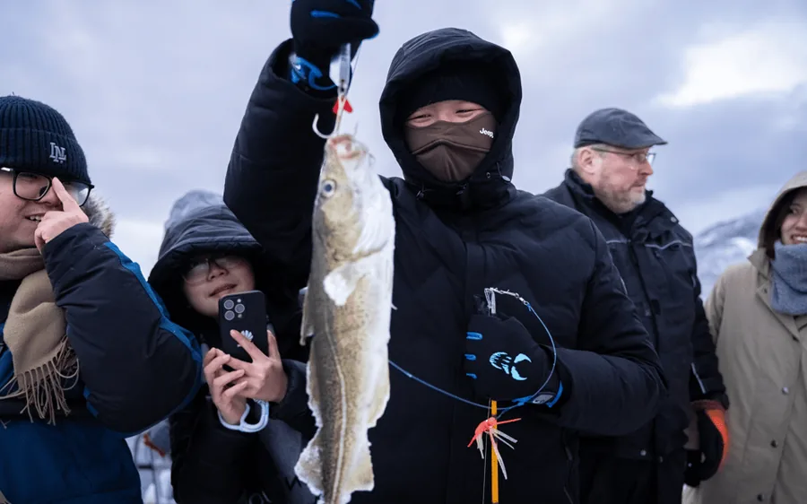 Guests holding their catch on deck in falling snow